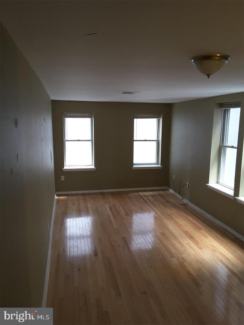 empty room with hardwood / wood-style floors, visible vents, and baseboards