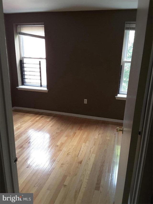 unfurnished room with baseboards and hardwood / wood-style flooring