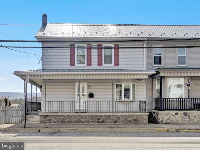 view of front of property with metal roof, a porch, and fence