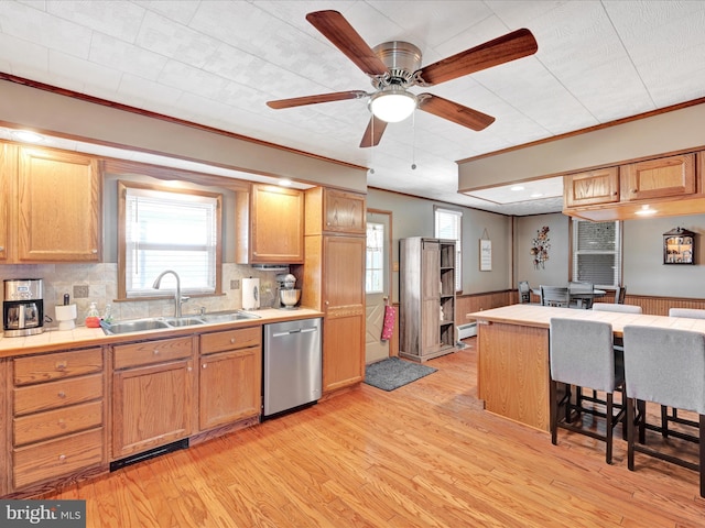 kitchen with dishwasher, tile counters, light wood-type flooring, and a sink