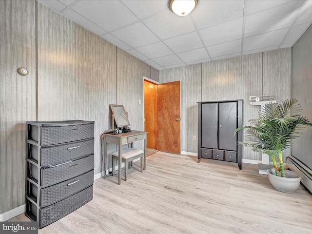 misc room with a drop ceiling, baseboards, and wood finished floors