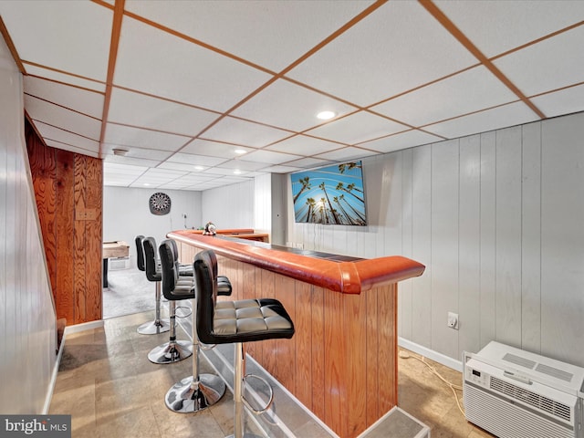 bar with a wall unit AC, recessed lighting, a drop ceiling, wood walls, and a dry bar