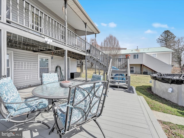 wooden deck featuring a covered pool, stairway, and outdoor dining space