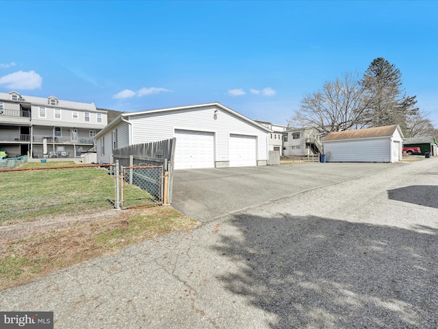 view of side of home with a gate, fence, a yard, a garage, and aphalt driveway