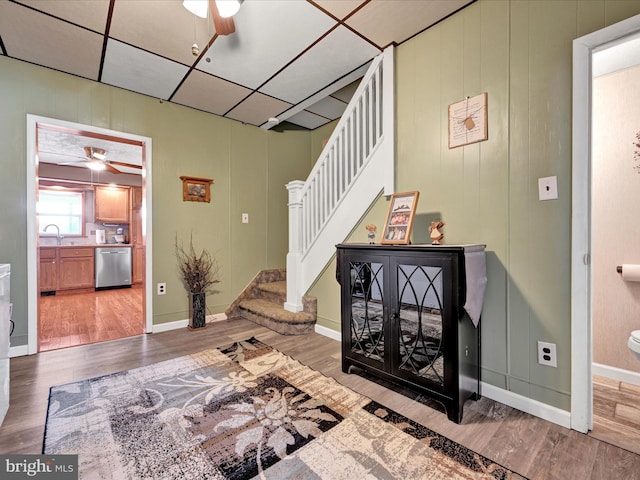 interior space with baseboards, a paneled ceiling, wood finished floors, and a ceiling fan