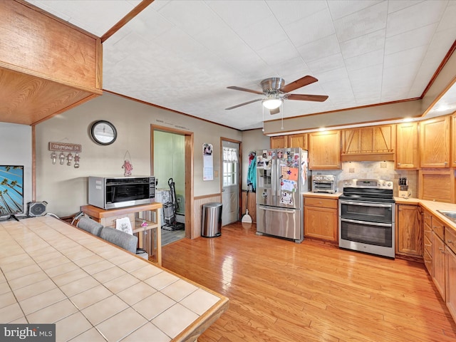 kitchen featuring light wood-type flooring, stainless steel appliances, crown molding, decorative backsplash, and ceiling fan