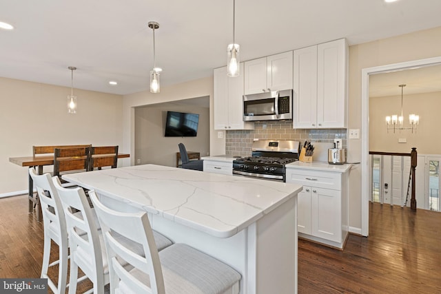 kitchen featuring light stone counters, backsplash, dark wood-style floors, stainless steel appliances, and white cabinets