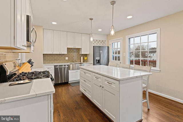 kitchen with a sink, stainless steel appliances, dark wood-type flooring, and white cabinetry