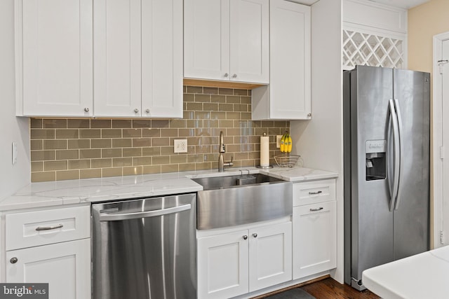 kitchen with light stone counters, a sink, stainless steel appliances, white cabinets, and tasteful backsplash