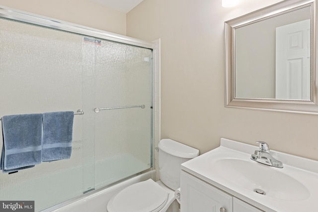 full bathroom with combined bath / shower with glass door, toilet, and vanity