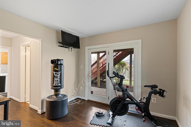 exercise room with baseboards and dark wood-type flooring