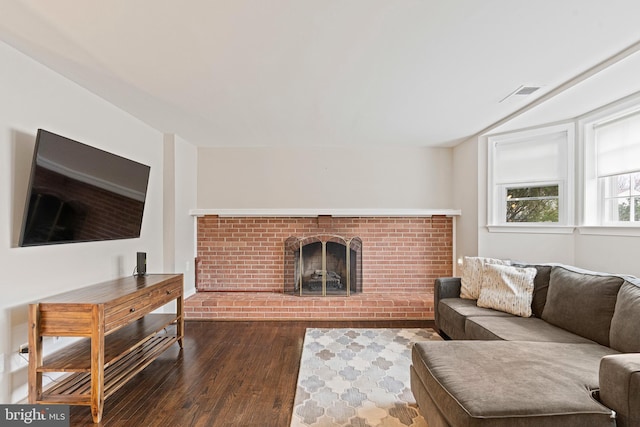 living room with visible vents, a fireplace, and wood finished floors