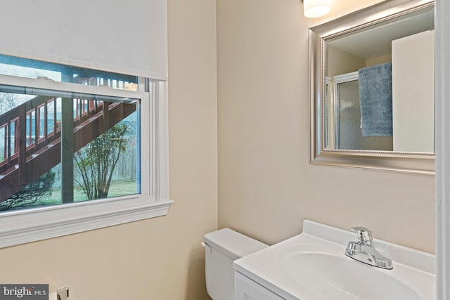 bathroom featuring an enclosed shower, toilet, and vanity