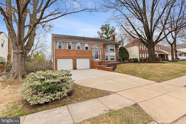 split foyer home featuring brick siding, fence, concrete driveway, a chimney, and an attached garage