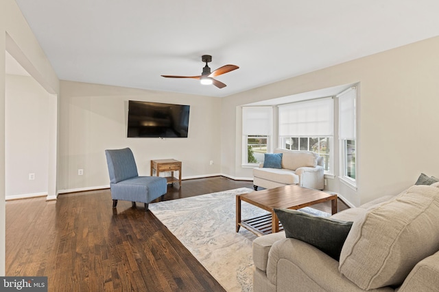 living room with dark wood-type flooring, baseboards, and ceiling fan