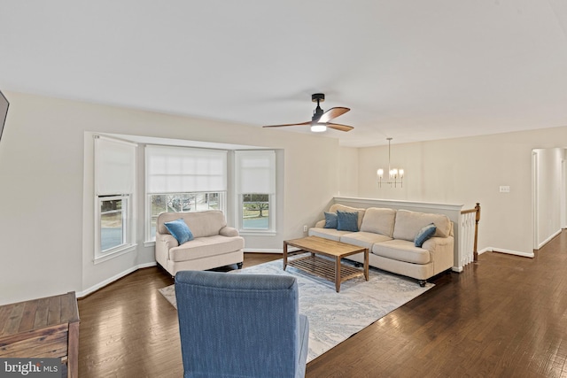 living room featuring baseboards, dark wood-style floors, and ceiling fan with notable chandelier