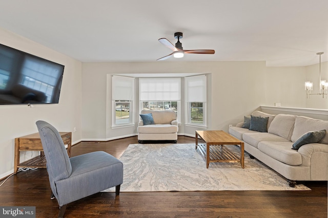 living area featuring baseboards, wood finished floors, and ceiling fan with notable chandelier