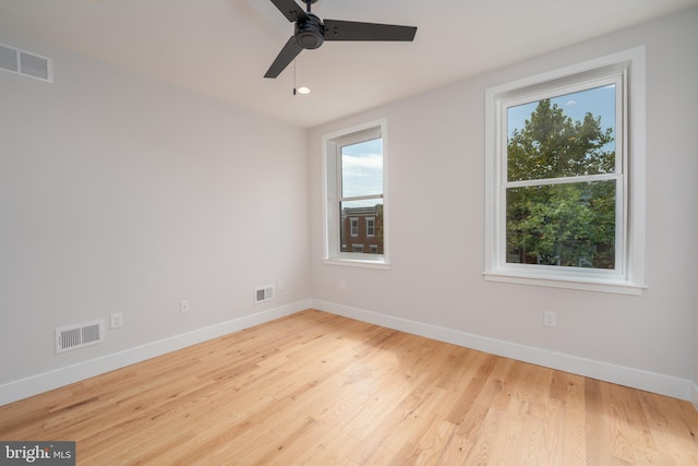 spare room featuring visible vents, baseboards, ceiling fan, and wood finished floors