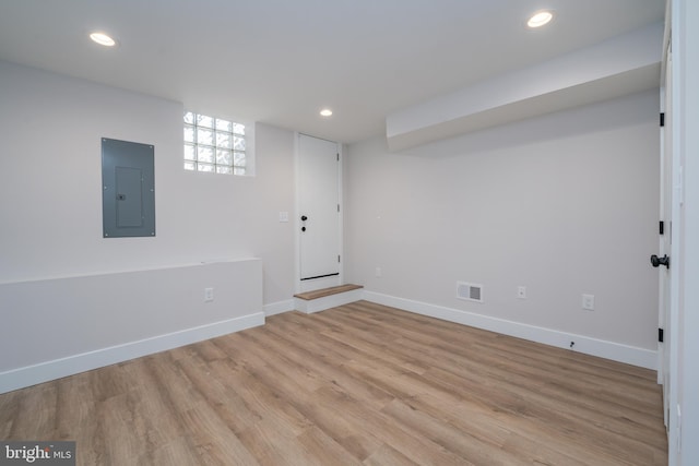 below grade area with electric panel, visible vents, light wood-style flooring, and recessed lighting