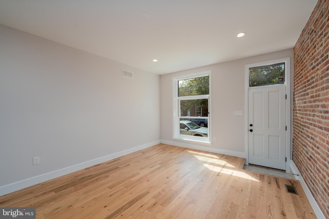 interior space with visible vents, baseboards, light wood-style floors, and brick wall