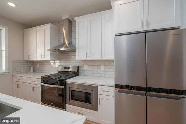 kitchen featuring stainless steel appliances, white cabinets, and wall chimney range hood