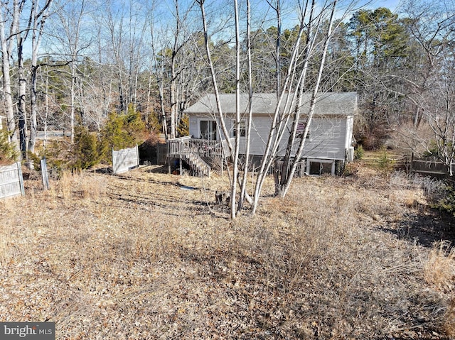 exterior space with roof with shingles, stairs, a deck, and fence