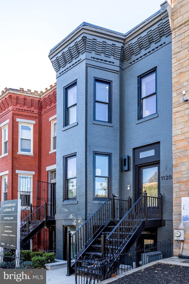 view of property featuring stairway and brick siding