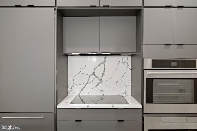 kitchen featuring light countertops, black electric stovetop, gray cabinets, and backsplash