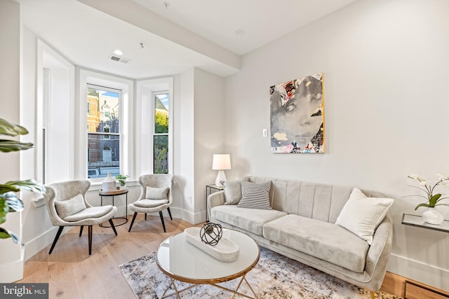 living room featuring light wood-type flooring, visible vents, and baseboards