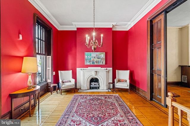 living area featuring crown molding, baseboards, a fireplace, an inviting chandelier, and wood finished floors