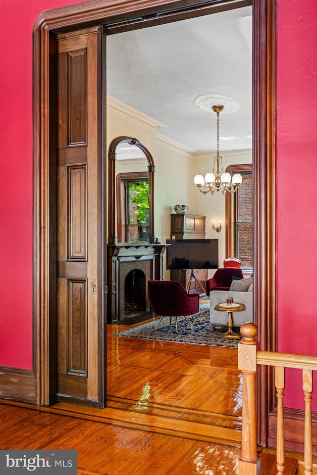 entrance foyer featuring hardwood / wood-style floors, an inviting chandelier, crown molding, and a fireplace