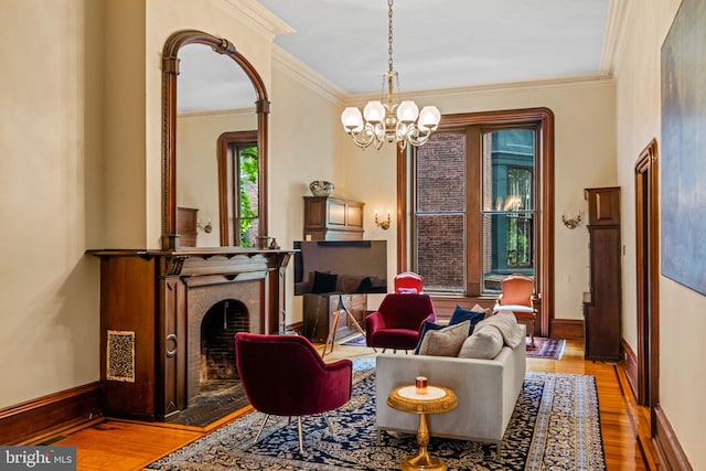 living area featuring an inviting chandelier, wood finished floors, a fireplace, and crown molding