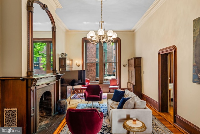 living area with ornamental molding, wood finished floors, baseboards, and a chandelier