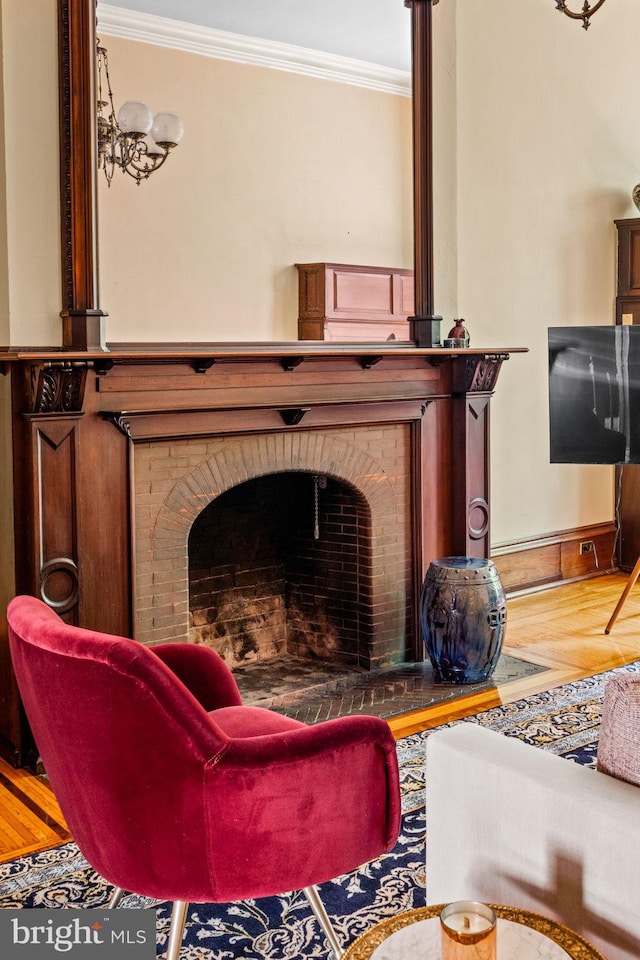 living room with a brick fireplace, wood finished floors, baseboards, and ornamental molding