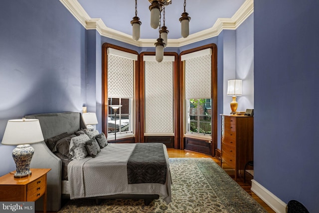 bedroom with baseboards, wood finished floors, and crown molding