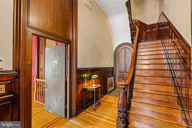 stairs with a wainscoted wall and wood finished floors