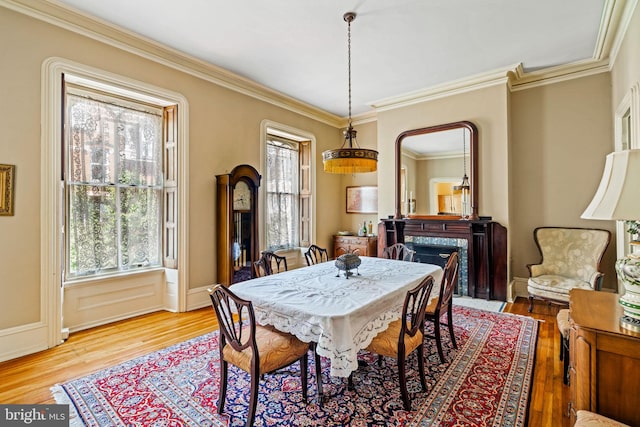 dining room featuring a high end fireplace, wood finished floors, and ornamental molding