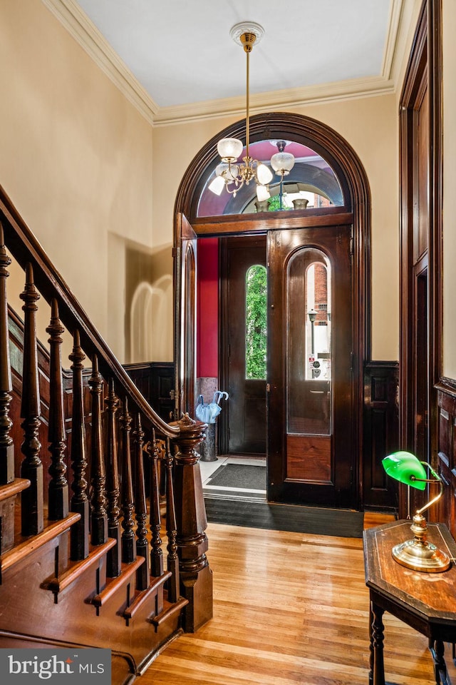 foyer featuring a chandelier, wainscoting, ornamental molding, and wood finished floors