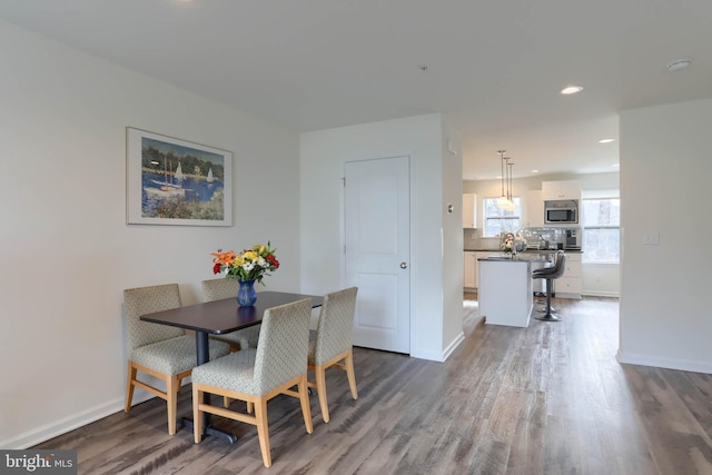 dining space featuring dark wood-type flooring and baseboards