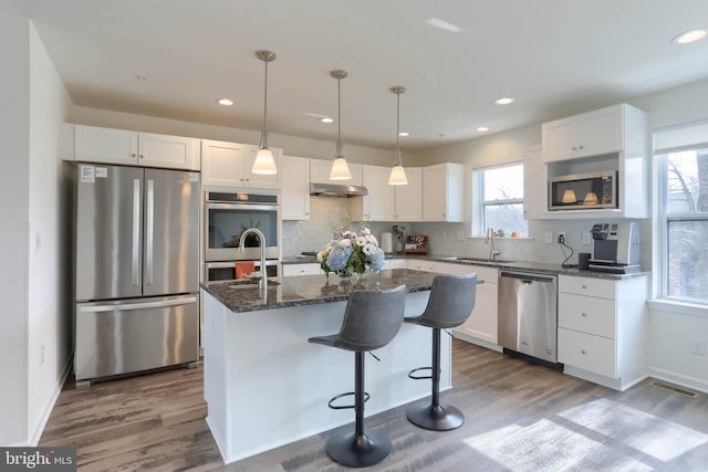 kitchen featuring white cabinetry, under cabinet range hood, visible vents, and appliances with stainless steel finishes