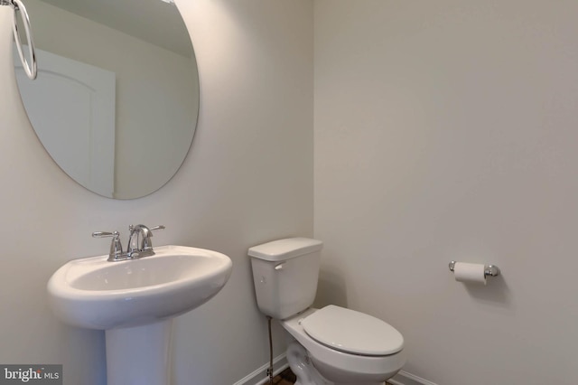 half bathroom with a sink, baseboards, and toilet