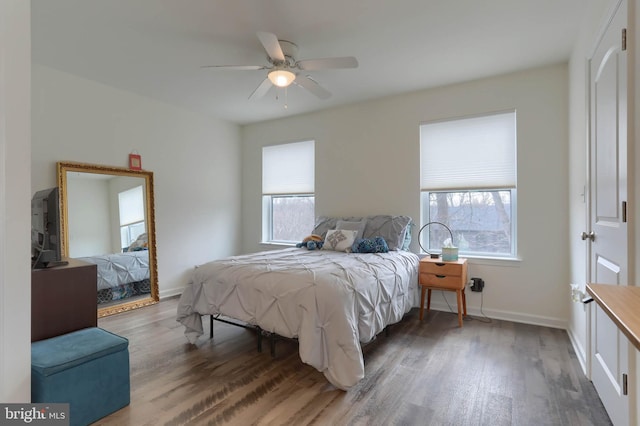 bedroom with a ceiling fan, baseboards, and wood finished floors