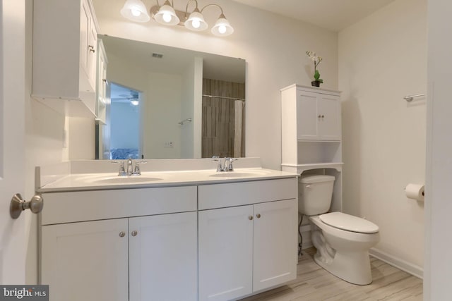 bathroom with double vanity, toilet, wood finished floors, and a sink