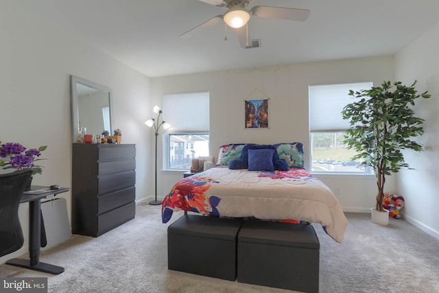 bedroom with visible vents, light colored carpet, baseboards, and ceiling fan