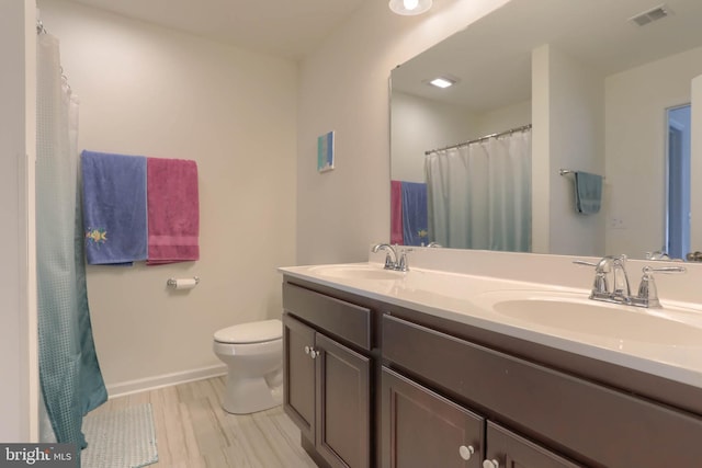 bathroom featuring double vanity, visible vents, toilet, and a sink