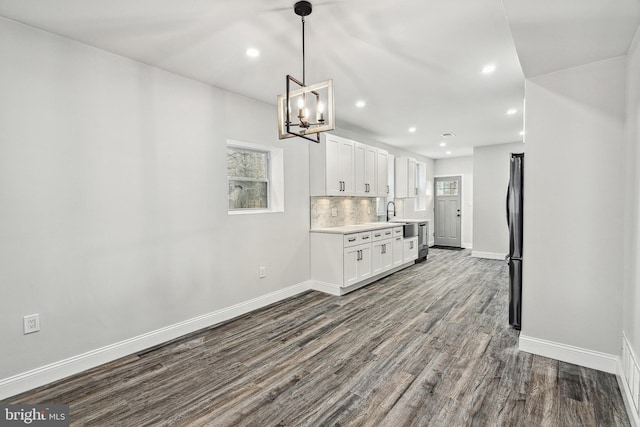 kitchen with dark wood finished floors, freestanding refrigerator, light countertops, white cabinets, and tasteful backsplash