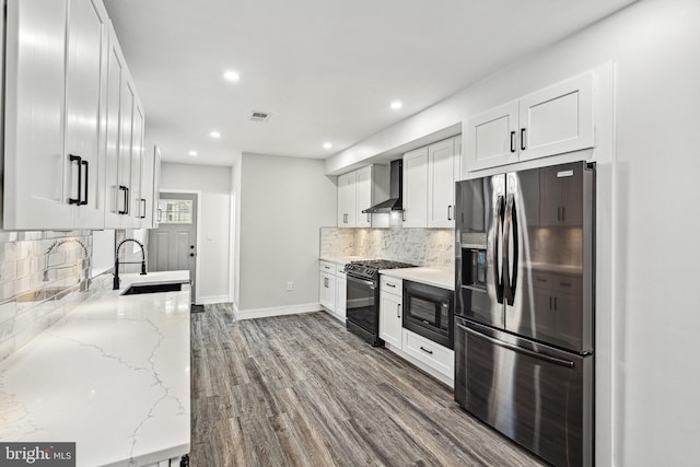 kitchen with stainless steel fridge with ice dispenser, a sink, gas range oven, black microwave, and wall chimney range hood