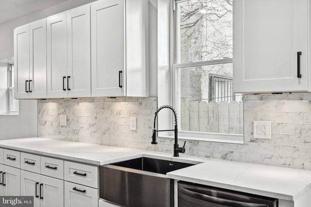 kitchen featuring a sink, tasteful backsplash, white cabinets, light stone countertops, and dishwasher