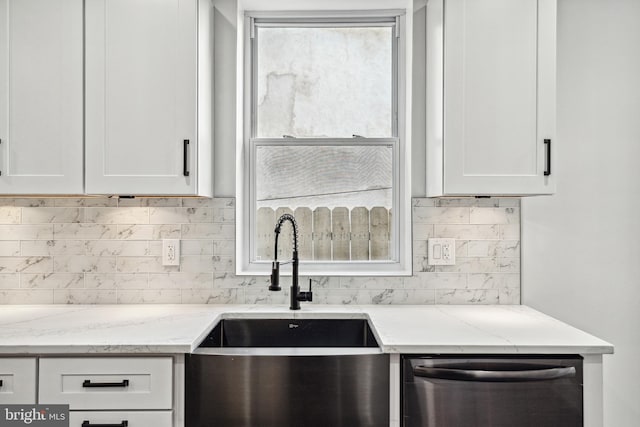 kitchen featuring stainless steel dishwasher, light stone countertops, white cabinetry, and a sink