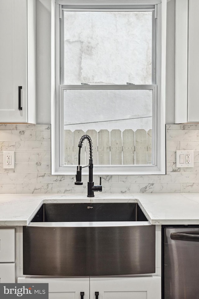 interior details with a sink, decorative backsplash, light stone countertops, and white cabinets